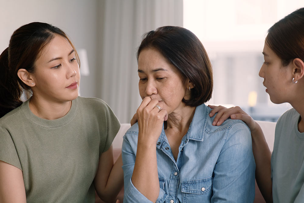 Two adult female children talk to their senior mother about her medical care.